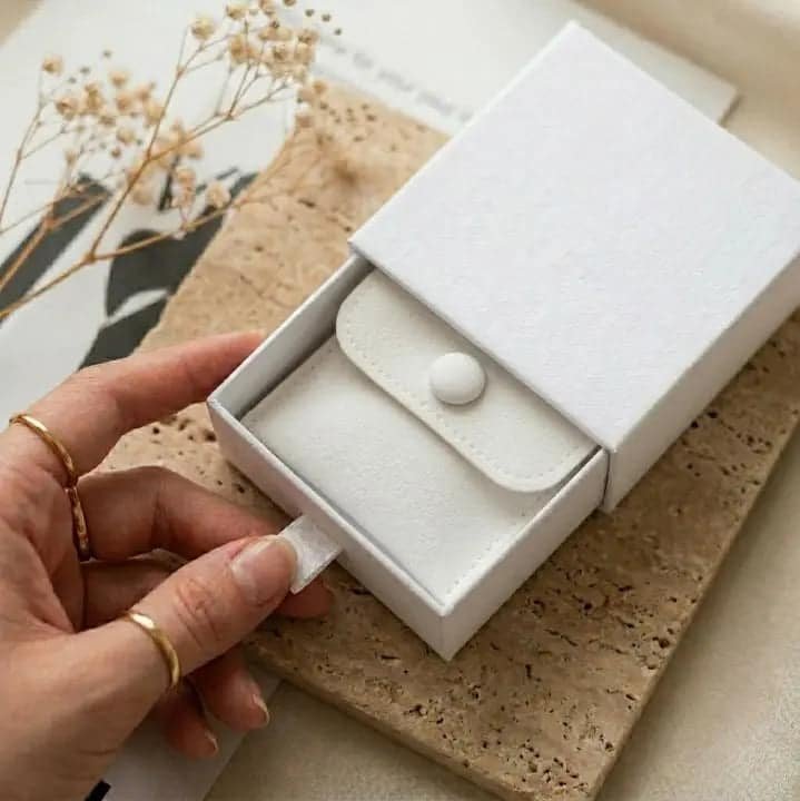 Écrin blanc et pochette de La Box Bijoux BB ouverts à la main