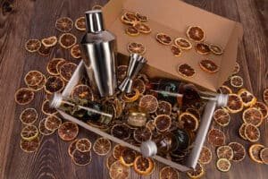 Box Cocktails ouverte avec shaker, ustensiles et agrumes séchés